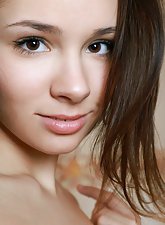 Naked short-haired brunette stunner poses naked next to a bathtub