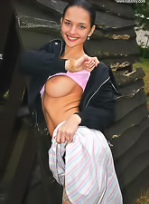 Busty teen gal Katie Fey takes off her pink top and shows her round breasts.