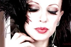 Glam lady in leather corset and with piercings all over her body opens her pussy lips on a chair